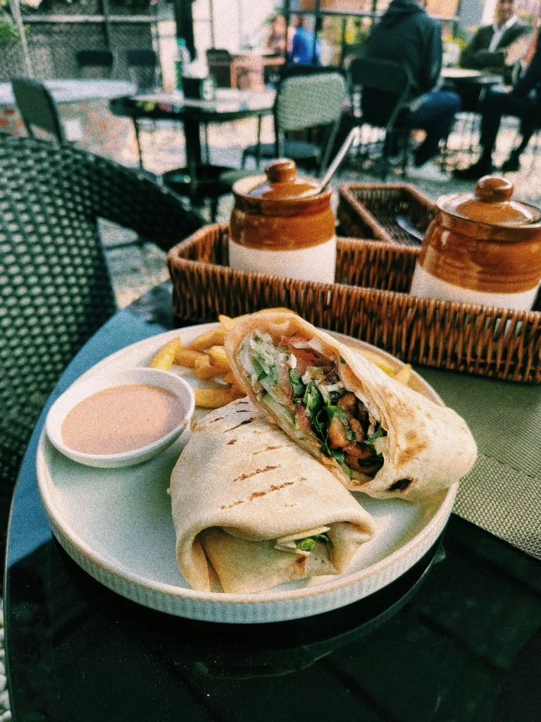 Delicious wrapped sandwich served with fries and sauce on a restaurant table.